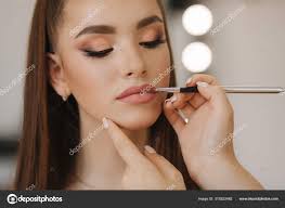 makeup artist applies lipstick hand of