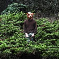Man wearing bear mask while standing amidst plants - Stock Photo - Dissolve