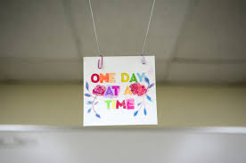 a handmade sign reading one day at a time hangs above the meeting
