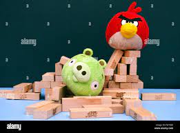 Angry Bird vs. Bad Piggies. Red bird broke bad pig's house. Bad piggy lying  in pile of Jenga bricks which its house was made out Stock Photo - Alamy
