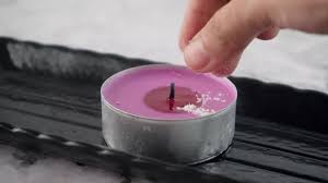 Hand sprinkling a pinch of salt on a purple candle from WikiHow