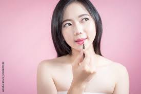 asian woman applying pink lipstick on