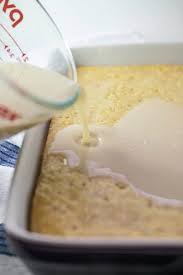 sweetened condensed coconut macadamia milk is poured over a baked vegan sponge cake with holes