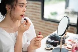 pretty asian female applies lipstick