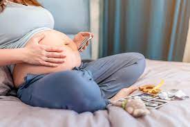 A Pregnant Woman Is Sitting On The Bed