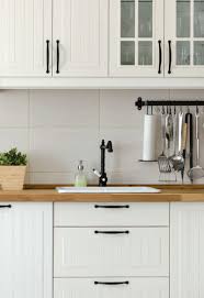 Clean white kitchen cabinets with black hardware in a minimalist kitchen. 35 Kitchen Cabinet Hardware Ideas For Every Design Style