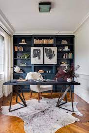 A stylish home office with grey walls, a white shelving unit, a fireplace and black leather chairs. 28 Dreamy Home Offices With Libraries For Creative Inspiration Feminine Home Offices Home Office Design Modern Home Office